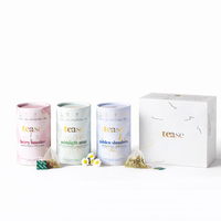 Tease Wellness Organics Gift Set with Berry Booster, Midnight Mint, and Golden Slumber tea blends in pastel cylindrical tins .