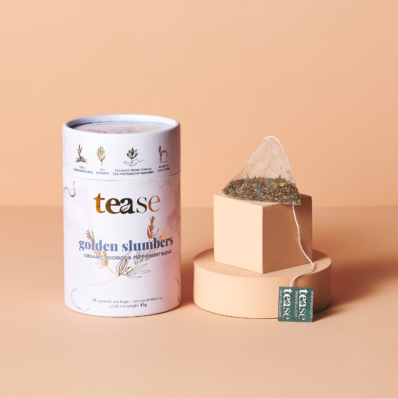 Golden Slumbers organic tea tube styled with loose botanicals and a warm glass of tea