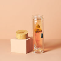 Tease Wellness 3 in 1 Sustainable Glass and Bamboo Tea Tumbler with Cinnamon tea blend steeping, wooden lid beside tumbler.