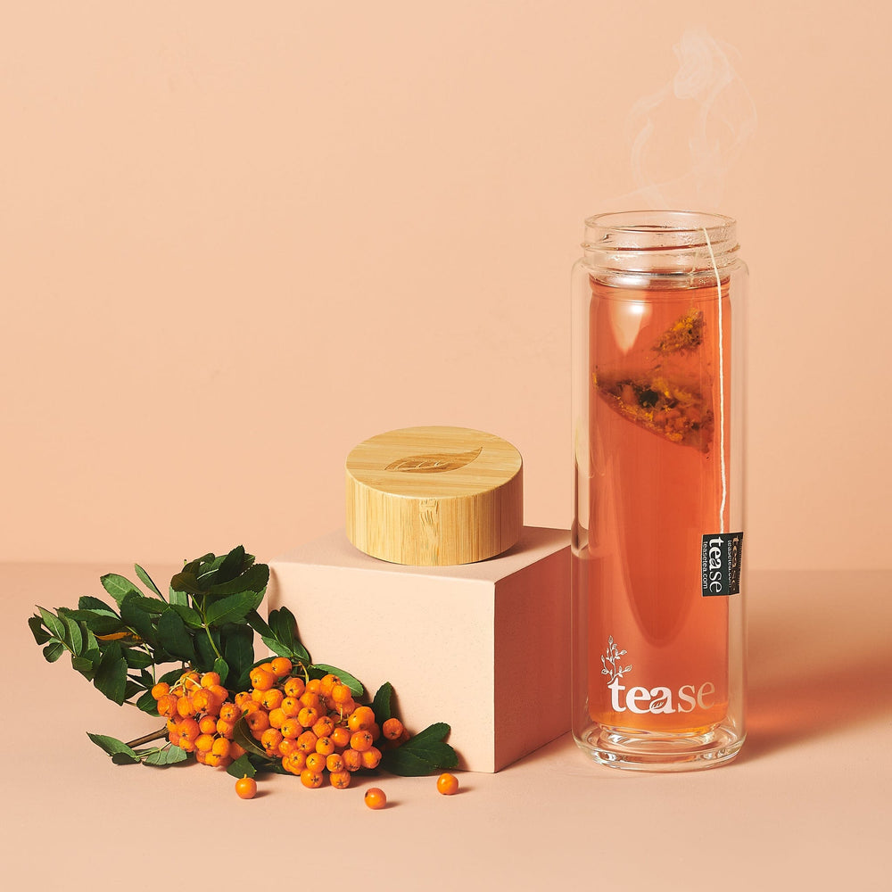 Tease Wellness 3 in 1 Sustainable Glass and Bamboo Tea Tumbler with steaming cinnamon tea and bamboo lid displayed with.